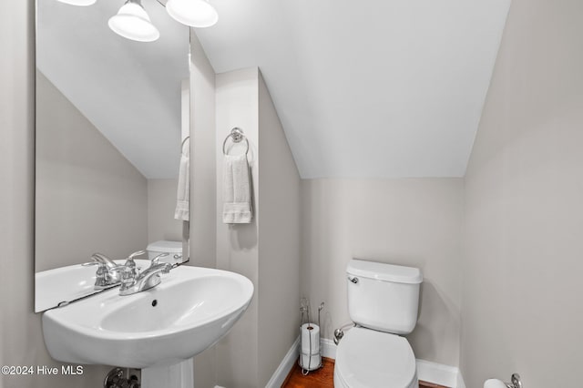 bathroom featuring toilet, sink, vaulted ceiling, and hardwood / wood-style flooring