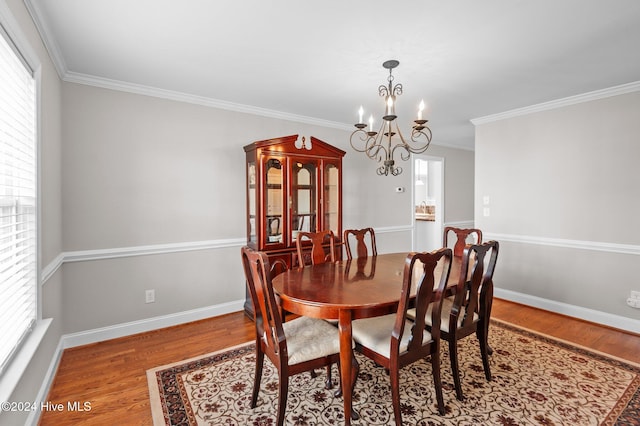 dining space featuring hardwood / wood-style floors, an inviting chandelier, and ornamental molding