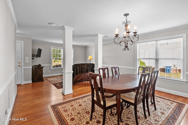 dining space featuring decorative columns, an inviting chandelier, light hardwood / wood-style flooring, and ornamental molding