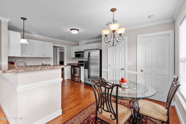 kitchen featuring stainless steel appliances, ornamental molding, decorative light fixtures, a chandelier, and dark hardwood / wood-style flooring