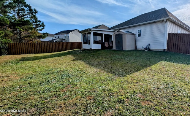 rear view of house featuring a sunroom, a storage unit, and a lawn