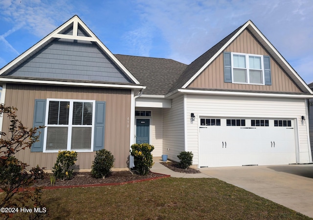 craftsman inspired home featuring a garage and a front lawn