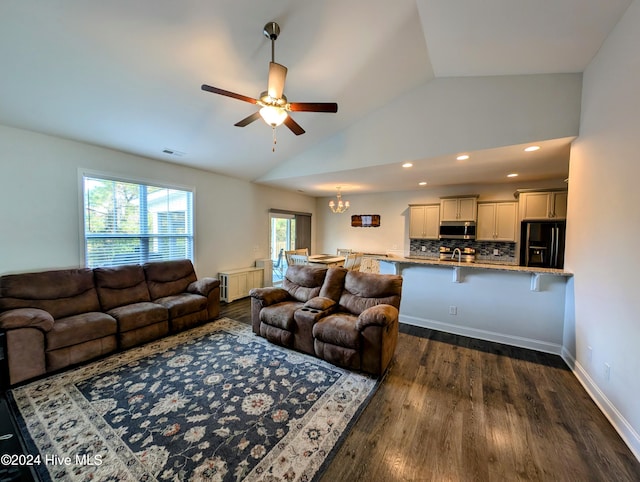 living room with ceiling fan with notable chandelier, dark wood-type flooring, and vaulted ceiling