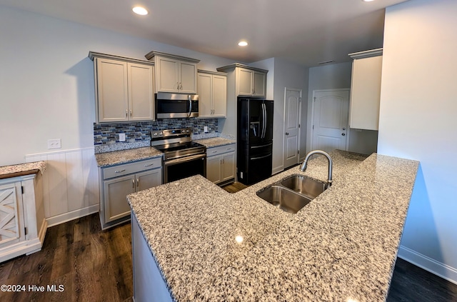 kitchen featuring light stone countertops, kitchen peninsula, sink, and appliances with stainless steel finishes