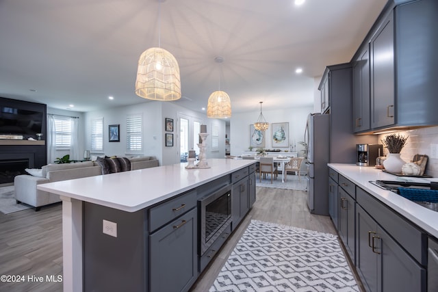 kitchen featuring decorative light fixtures, a kitchen island, light hardwood / wood-style floors, and stainless steel appliances