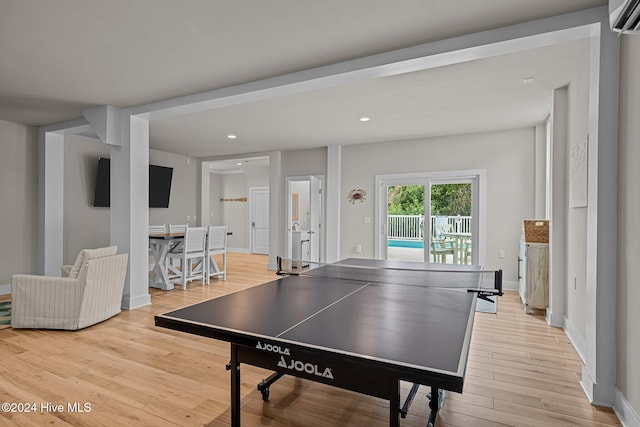 recreation room featuring a wall mounted AC and light hardwood / wood-style floors