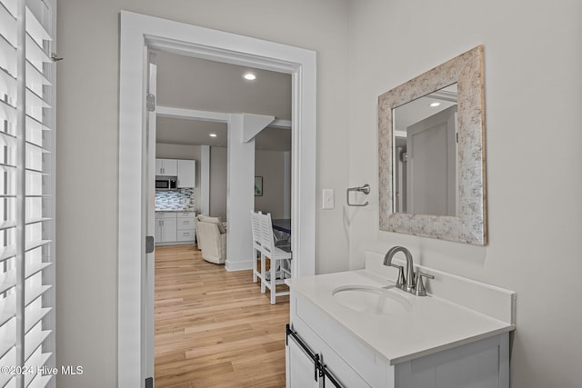 bathroom featuring wood-type flooring, vanity, and decorative backsplash