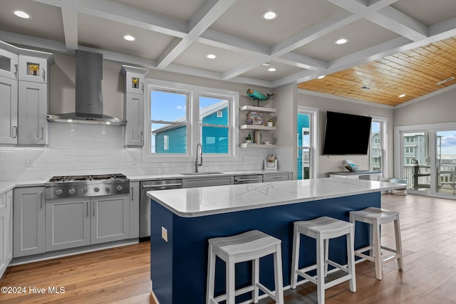 kitchen with appliances with stainless steel finishes, wall chimney range hood, a kitchen island, and backsplash