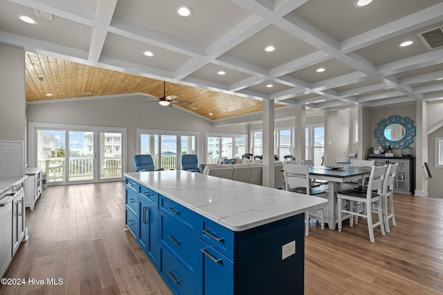 kitchen featuring plenty of natural light, light wood-type flooring, a kitchen island, and blue cabinets