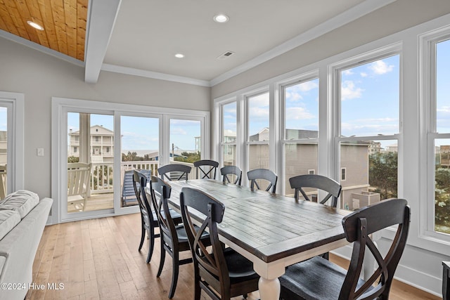 dining space with light wood-type flooring, lofted ceiling, a healthy amount of sunlight, and crown molding