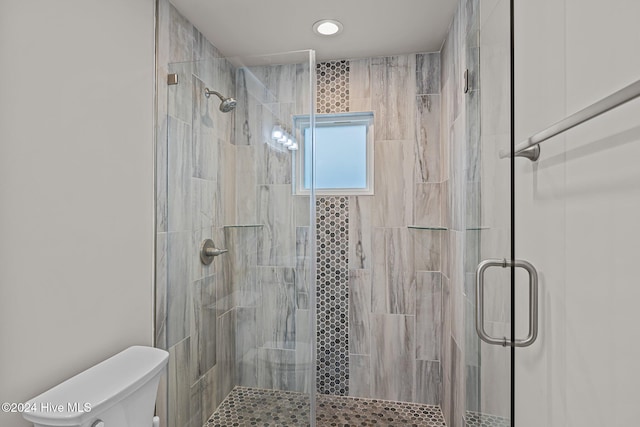 bathroom featuring a shower with door and toilet