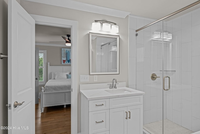 bathroom featuring walk in shower, hardwood / wood-style flooring, ceiling fan, vanity, and crown molding