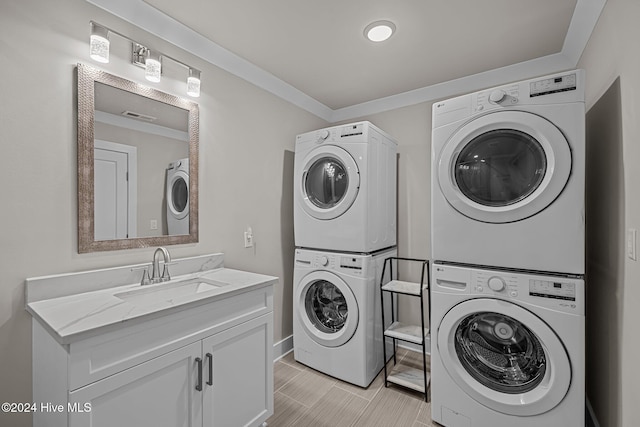 laundry area featuring stacked washer / drying machine, cabinets, and sink