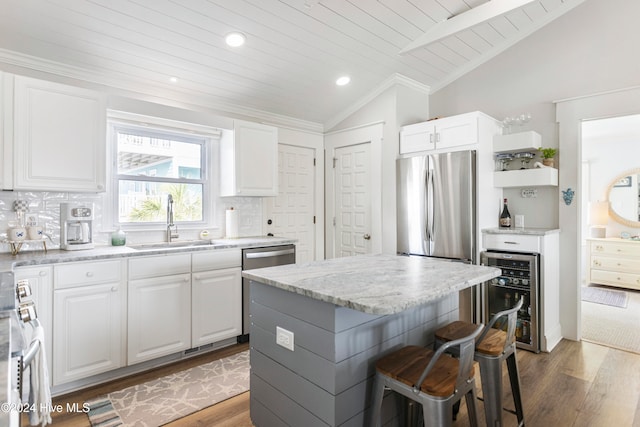 kitchen featuring wine cooler, a kitchen island, white cabinetry, stainless steel refrigerator, and lofted ceiling