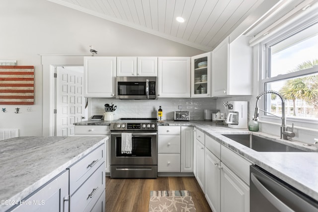 kitchen with dark wood-type flooring, white cabinets, vaulted ceiling, and stainless steel appliances