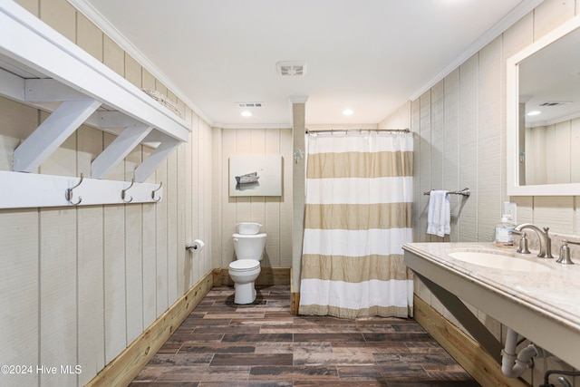 bathroom with toilet, wood walls, hardwood / wood-style flooring, sink, and ornamental molding