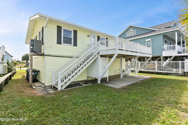 back of house with central AC unit, a lawn, and a wooden deck