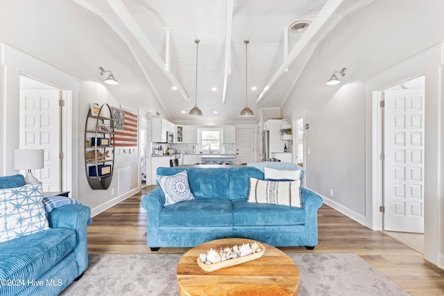 living room featuring light hardwood / wood-style floors and vaulted ceiling with beams