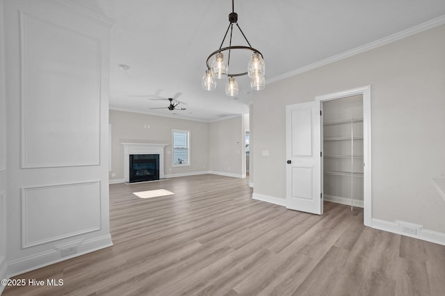 unfurnished living room with light wood-type flooring, ceiling fan with notable chandelier, built in features, and crown molding