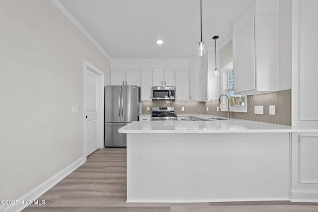 kitchen featuring hanging light fixtures, sink, kitchen peninsula, appliances with stainless steel finishes, and white cabinetry