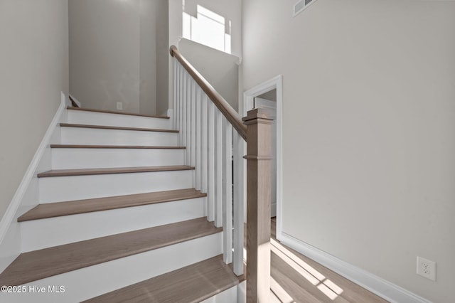 stairs with wood-type flooring and a high ceiling