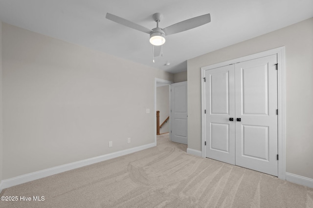 unfurnished bedroom featuring ceiling fan, light carpet, and a closet