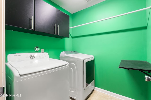 washroom with cabinets, light tile patterned flooring, and washer and clothes dryer