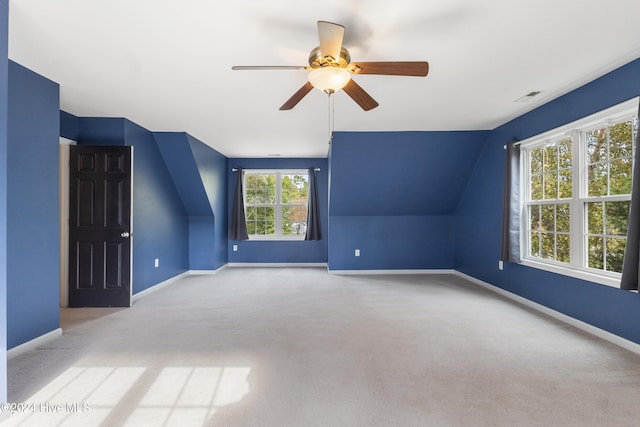 additional living space with ceiling fan, a wealth of natural light, light colored carpet, and lofted ceiling