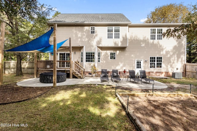 back of house with a wooden deck, cooling unit, a lawn, and a patio