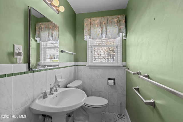 bathroom with toilet, tile walls, sink, and plenty of natural light