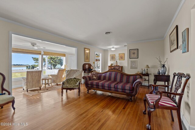 living room with light wood-type flooring, ceiling fan, and crown molding