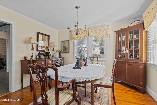 dining area with light wood-type flooring, a notable chandelier, and crown molding