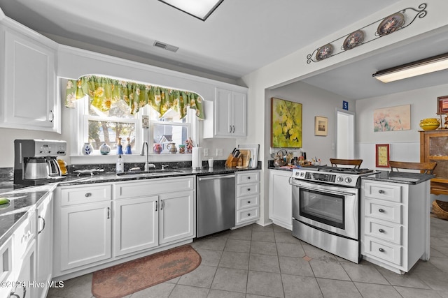 1701 Front St, Beaufort, NC 28516 - kitchen featuring appliances with stainless steel finishes, a sink, a peninsula, white cabinetry, and light tile patterned floors