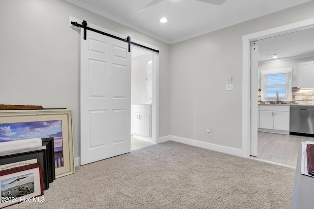 unfurnished living room with light carpet, a barn door, and sink