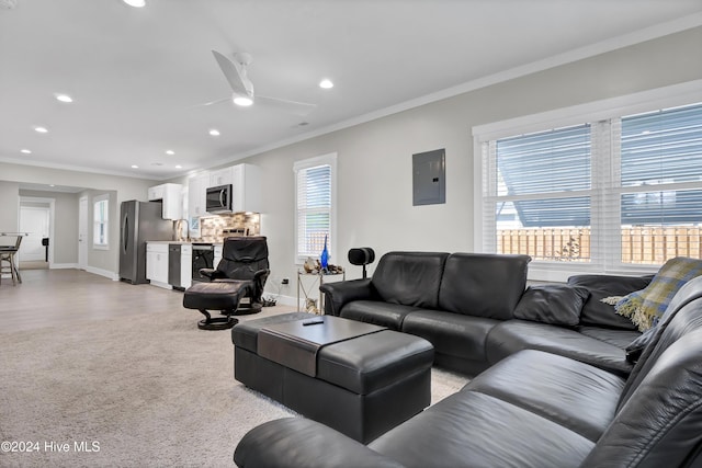 living room with electric panel, a wealth of natural light, ornamental molding, and ceiling fan