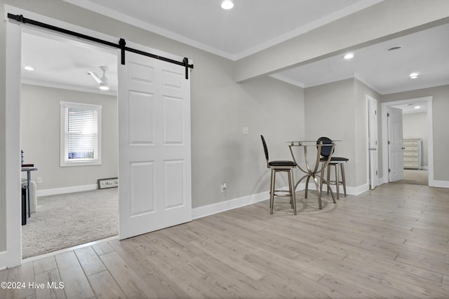 dining room with a barn door, crown molding, and light hardwood / wood-style flooring