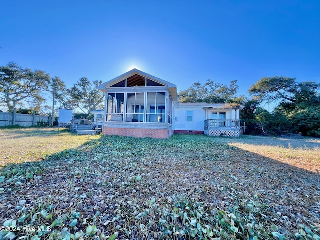 rear view of house featuring a sunroom, a yard, and a deck