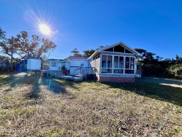 rear view of property with a sunroom, a yard, and a wooden deck