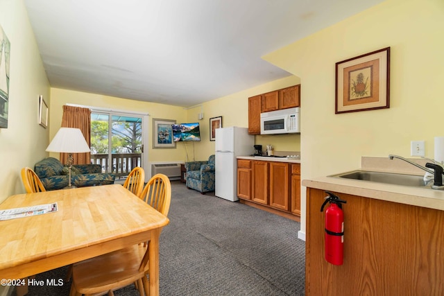 kitchen featuring white appliances, dark carpet, a wall mounted AC, and sink