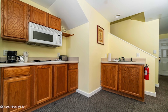 kitchen with lofted ceiling, sink, dark carpet, and white appliances