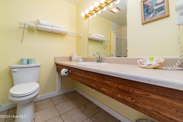 bathroom featuring tile patterned floors, toilet, sink, and walk in shower