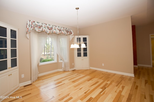 unfurnished dining area with light hardwood / wood-style floors and an inviting chandelier