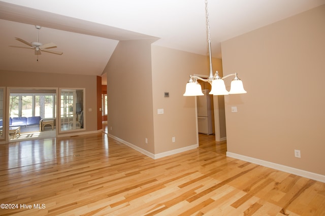 unfurnished room featuring ceiling fan with notable chandelier, vaulted ceiling, and light hardwood / wood-style flooring