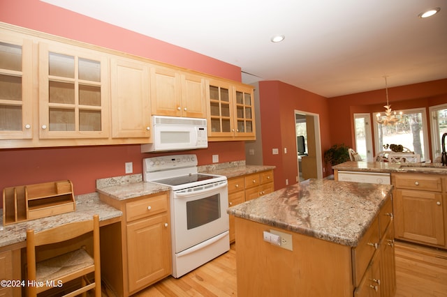 kitchen featuring white appliances, sink, decorative light fixtures, a center island, and light hardwood / wood-style floors