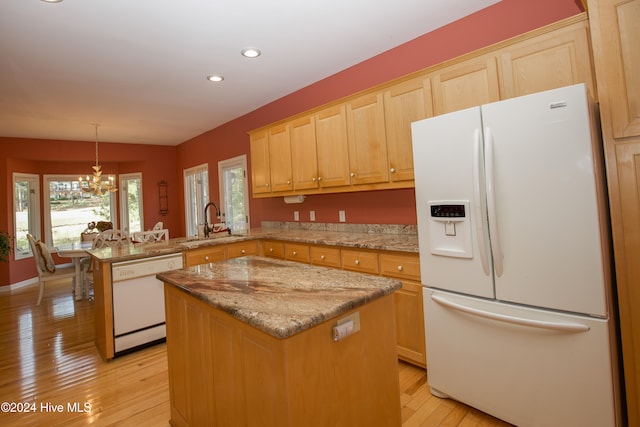 kitchen featuring kitchen peninsula, white appliances, a center island, and light hardwood / wood-style flooring