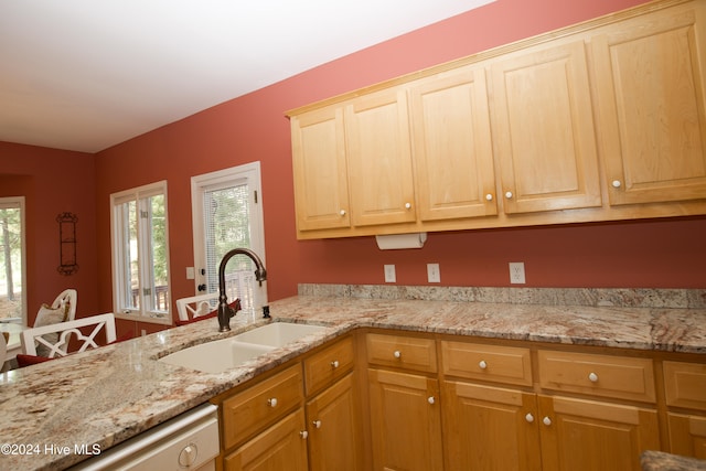 kitchen with dishwasher, kitchen peninsula, light stone countertops, and sink