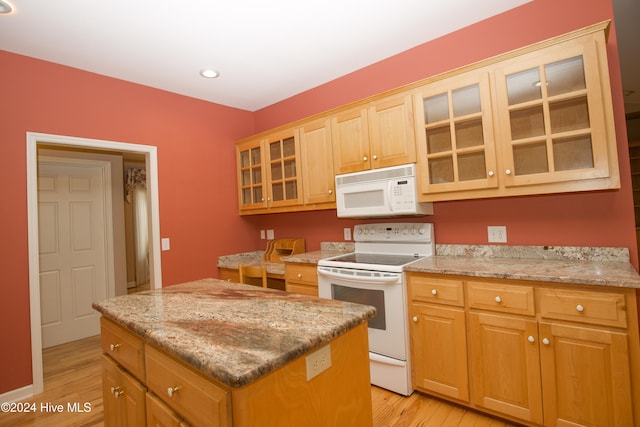 kitchen featuring a center island, light wood-type flooring, white appliances, and light stone counters