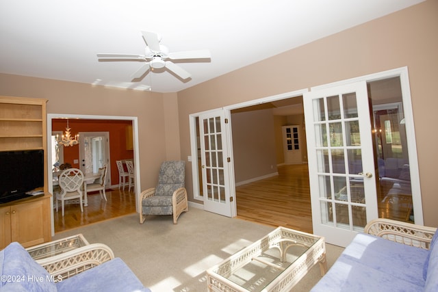 living room featuring french doors, ceiling fan with notable chandelier, and hardwood / wood-style flooring