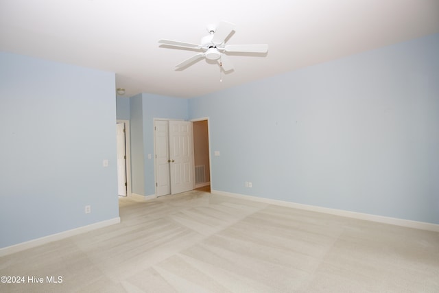 spare room with ceiling fan and light colored carpet