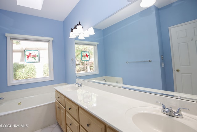 bathroom with tile patterned floors, a skylight, vanity, and a healthy amount of sunlight